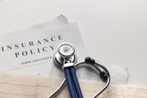 Explore Indiana Group Health Insurance options with help from Nefouse & Associates image shows stethoscope on top of insurance policy paperwork